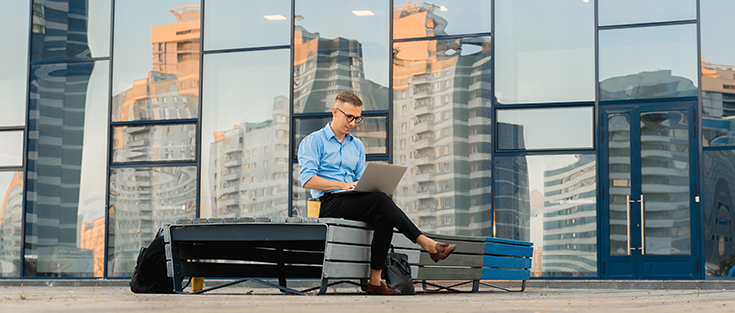 Businessman working on laptop outside of office building