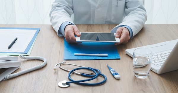 Professional doctor working at office desk, he is using a digital tablet, healthcare and technology concept